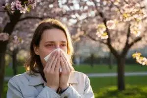 Personne allergique au pollen en période de floraison printanière, yeux rouges et mouchoir