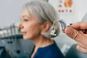 Appareil auditif contour d'oreille présenté devant une femme senior lors d'un rendez-vous en cabinet d'audioprothèse