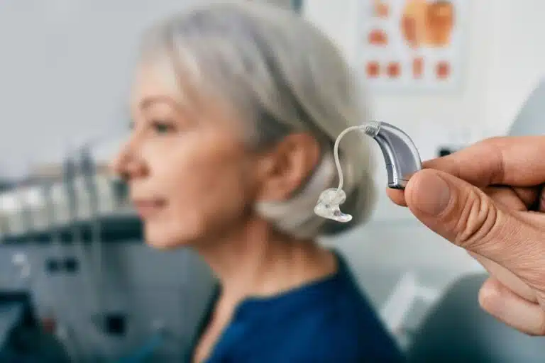 Appareil auditif contour d'oreille présenté devant une femme senior lors d'un rendez-vous en cabinet d'audioprothèse