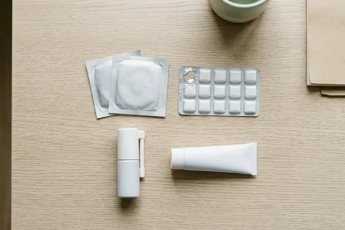 Les formes de substituts nicotiniques Patchs, gommes, pastilles et spray de nicotine posés sur une table en bois clair