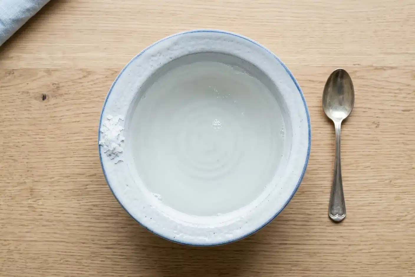 Gargarisme eau salée pour soulager le mal de gorge Bol blanc d'eau salée tiède sur table en bois, pour pratiquer un gargarisme contre le mal de gorge