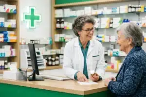 Pharmacienne au comptoir conseillant un patient sur le remboursement des substituts nicotiniques