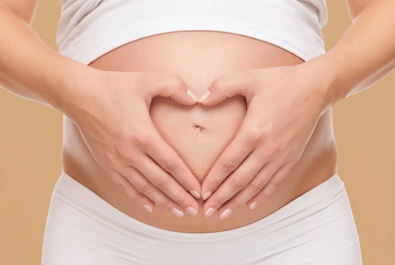 ventre Femme enceinte au 1er trimestre, assise à table, main sur ventre gonflé par les ballonnements