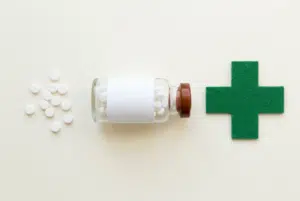 Flacon de comprimés de cortisone, cachets et croix verte de pharmacie illustrant la durée pendant laquelle la cortisone reste dans le corps