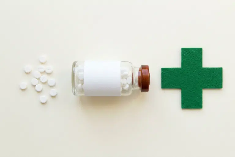 Flacon de comprimés de cortisone, cachets et croix verte de pharmacie illustrant la durée pendant laquelle la cortisone reste dans le corps
