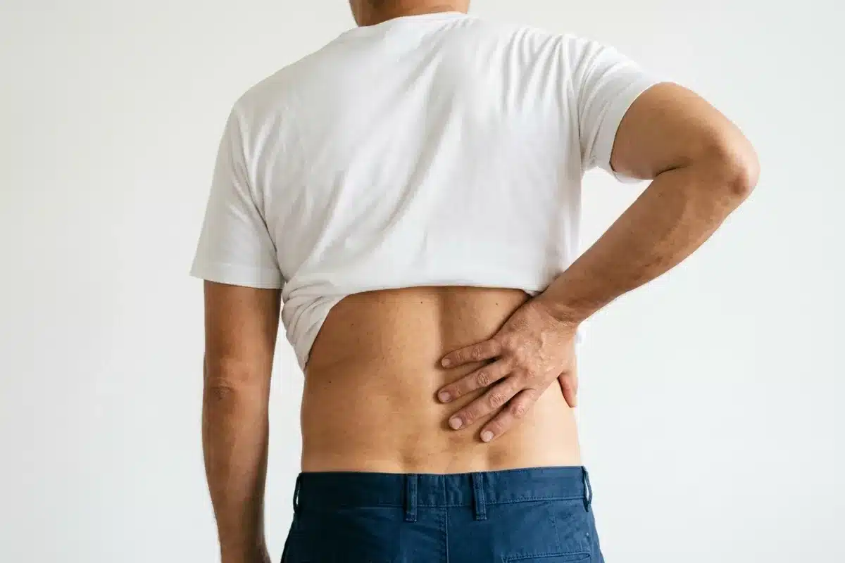 Homme tenant sa zone lombaire douloureuse, signe caractéristique d’une fracture de l’apophyse transverse